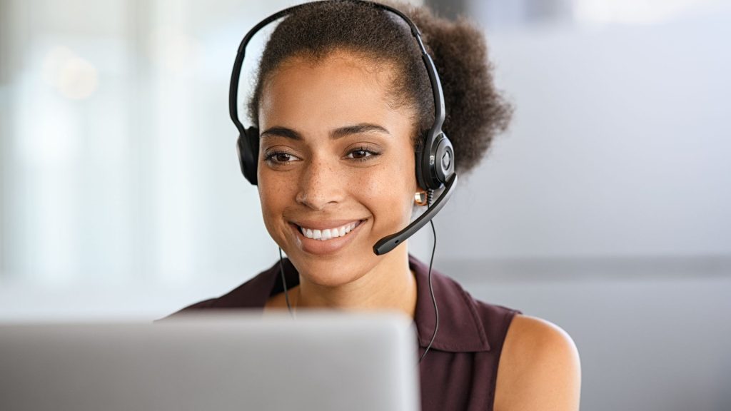 A woman wearing a headset in front of a laptop and providing support as canada virtual assistant
