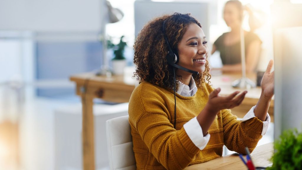 A woman in a headset is working on a computer as Virtual Real Estate Assistants