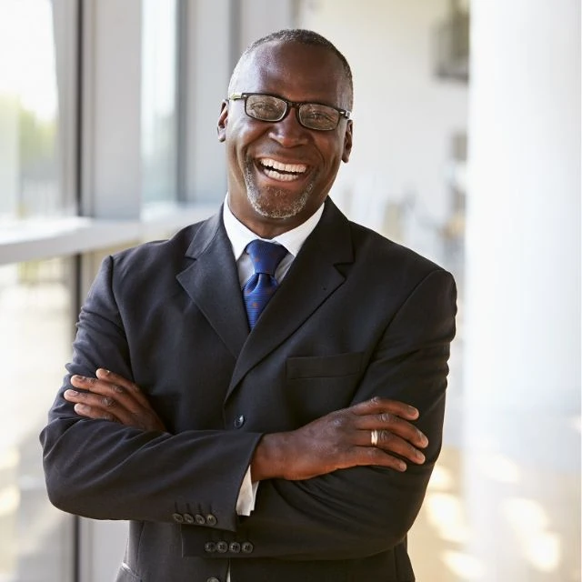 A smiling black businessman in a suit and tie.