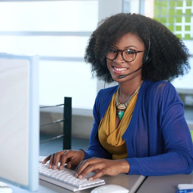 A black woman wearing a headset in front of a computer.