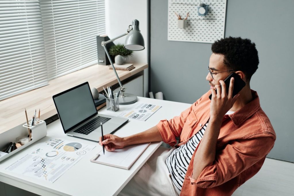 A man sitting at a desk and talking on the phone to Find Virtual Assistant
