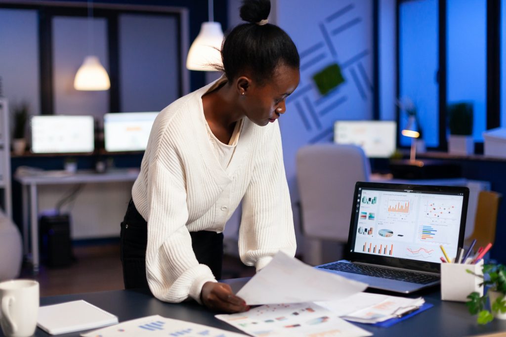 Black bookkeeper working on financial reports checking statistics