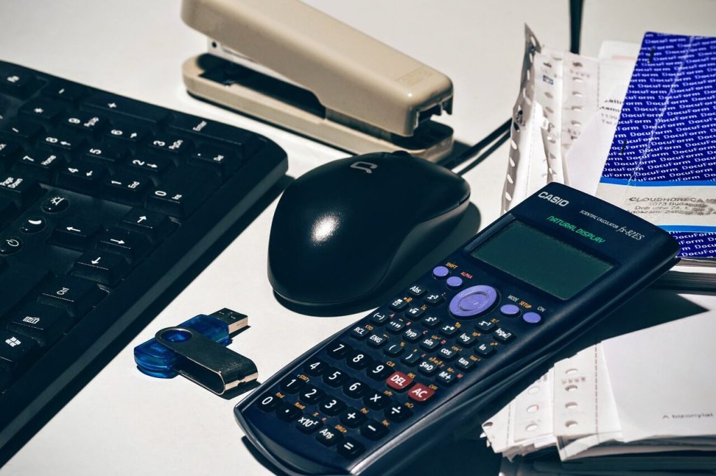 A calculator and mouse on a desk, used for bookkeeping services.